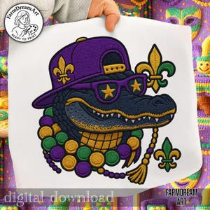 May include: Embroidered design featuring a purple alligator wearing a purple cap, star-shaped sunglasses, and a beaded necklace in Mardi Gras colors. The alligator has a fleur-de-lis on the cap and sunglasses. The words "digital download" are at the bottom.