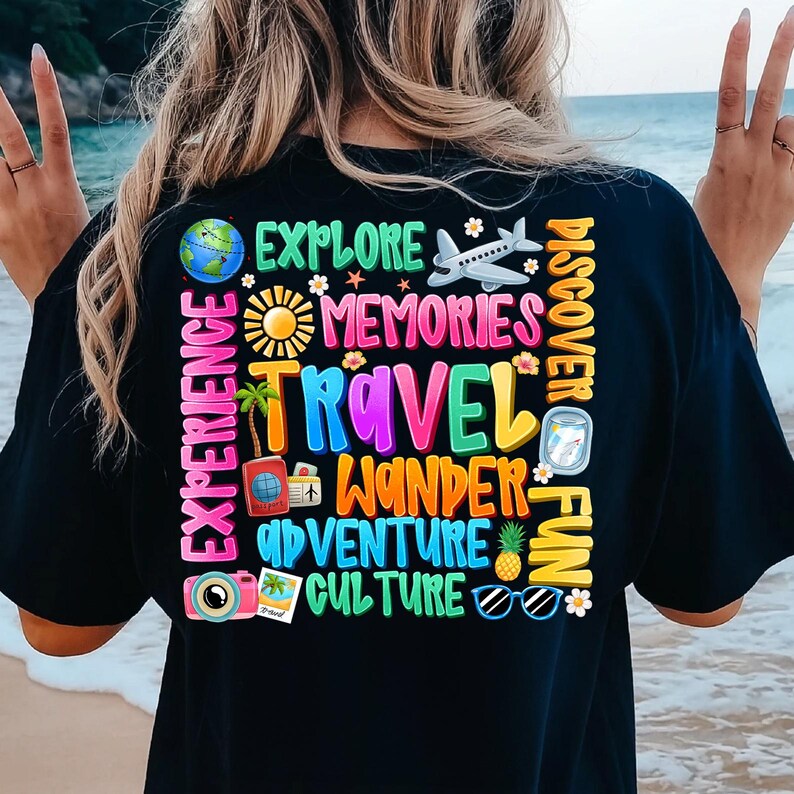 May include: Black t-shirt with a colorful graphic design featuring the words "Explore", "Memories", "Travel", "Wander", "Adventure", "Culture", "Discover", "Fun", and "Experience". The graphic also includes images of a globe, a plane, a sun, a palm tree, a camera, sunglasses, and a pineapple.