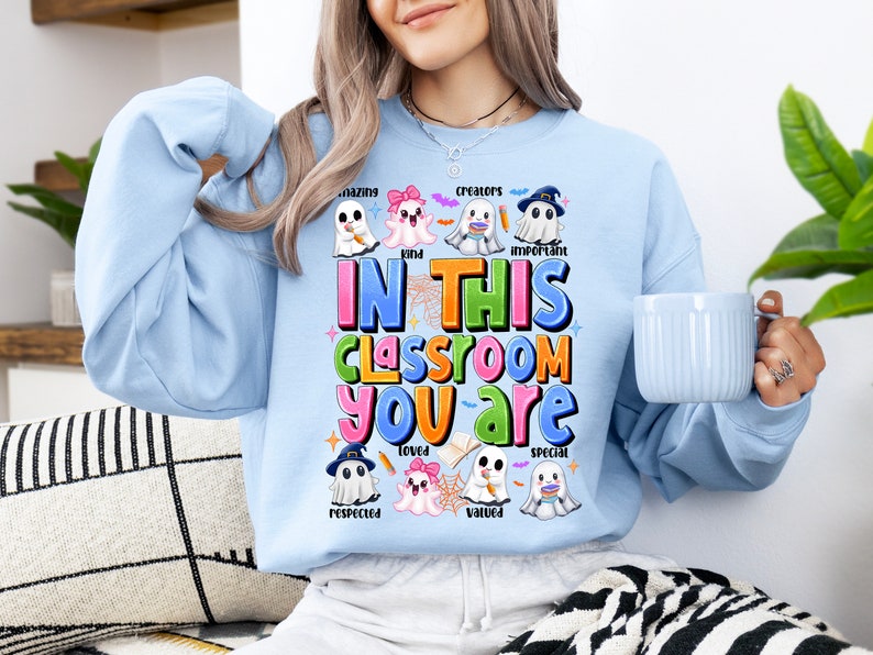 May include: Light blue sweatshirt with a colorful graphic of ghosts and the text "In this classroom you are amazing, kind, creators, loved, respected, valued, important, special".