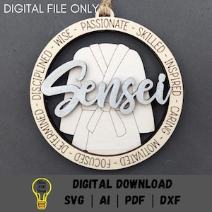 May include: A wooden circular ornament with the word "Sensei" in silver lettering. The ornament features a white karate gi with a black belt and the words "Disciplined - Wise - Passionate - Skilled - Inspired - Caring - Motivated - Focused" around the edge.
