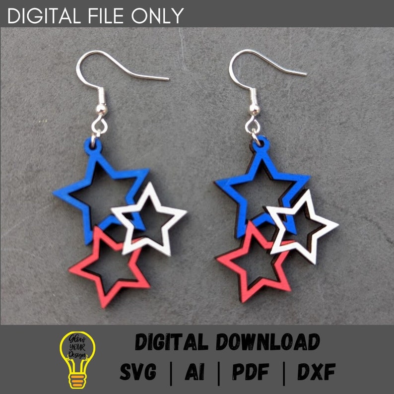 May include: A pair of red, white, and blue star-shaped earrings. The earrings are made of wood and have a layered design. The stars are nested inside each other, with the largest star on the bottom and the smallest star on top. The earrings are attached to silver hooks.