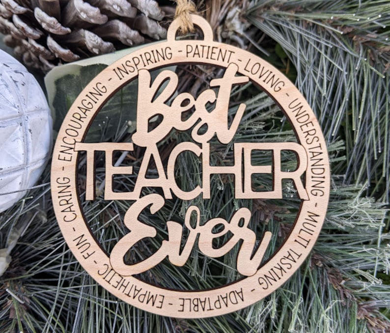Peut inclure: Ornement en bois avec le texte "Best Teacher Ever" entour&eacute; d'un cercle d'adjectifs positifs d&eacute;crivant un enseignant, tels que "inspirant", "patient", "aimant", "compr&eacute;hensif", "attentionn&eacute;", "amusant", "empathie", "adaptable" et "multit&acirc;che".