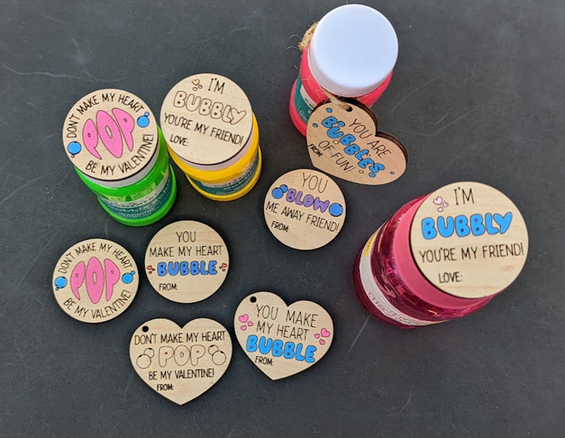 Puede incluir: Surtido de botellas de soluci&oacute;n de burbujas con tem&aacute;tica del D&iacute;a de San Valent&iacute;n con etiquetas de madera. Las etiquetas tienen varios mensajes, que incluyen "No hagas que mi coraz&oacute;n explote, &iexcl;s&eacute; mi Valent&iacute;n!" y "&iexcl;Eres burbujas de diversi&oacute;n!"