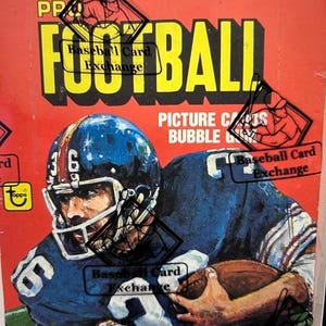 Puede incluir: Paquete de cartas de fútbol vintage con fondo rojo y la palabra "FOOTBALL" en letras amarillas grandes. La imagen presenta un jugador de fútbol americano con uniforme y casco azules. El paquete está etiquetado "Baseball Card Exchange".
