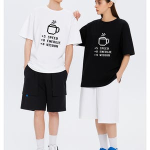 May include: White and black t-shirts with a pixelated coffee cup design and the text "+5 SPEED, +8 ENERGIE, +4 WISDOM." The shirts are worn with black and white shorts. The word "T-shirt" is at the top.