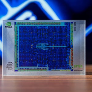 Könnte beinhalten: Nahaufnahme einer Grafikprozessoreinheit (GPU) mit blauem und grünem Leiterplattendesign. Die GPU ist mit "NVIDIA" und "GP104" beschriftet. Der Hintergrund ist mit blauer und weißer Beleuchtung verschwommen.