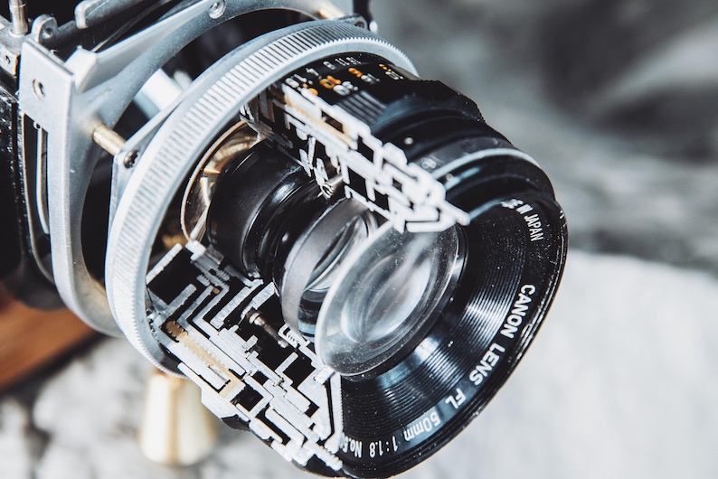 May include: A close-up of a silver and black Canon FL 50mm f/1.8 lens with the text "Canon Lens FL 50mm 1:1.8 Made in Japan" printed on the side.