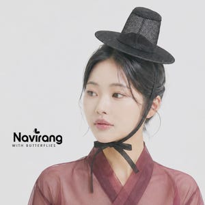 May include: A black gat, a traditional Korean hat, featuring a cylindrical crown and a wide brim made of a fine, semi-transparent mesh material. The hat is secured with thin black ribbons tied in a bow under the chin. Text reads Navirang WITH BUTTERFLIES.