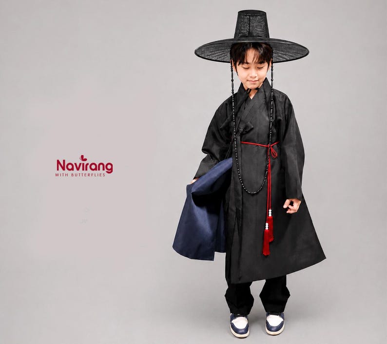 May include: A black traditional Korean hanbok robe with a matching wide-brimmed black hat, featuring a red waist tie with tassels and a long beaded necklace. The garment includes a navy blue inner layer and the text Navirang WITH BUTTERFLIES.