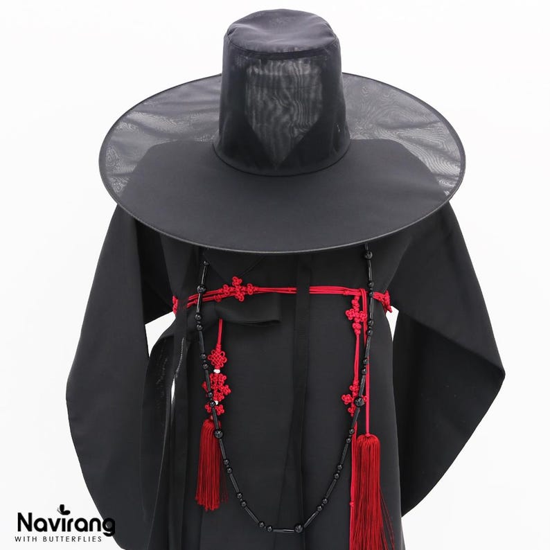 May include: A black traditional Korean hat with a wide, sheer brim and a tall, cylindrical crown, paired with a black robe featuring a red knotted cord accessory with long tassels and black beads draped across the front of the garment.