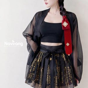May include: A black outfit featuring a sheer, long-sleeved outer layer, a cropped tank top, and a flared skirt with gold-coloured text patterns. A red velvet ribbon with gold-coloured decorative accents is attached to the shoulder area.