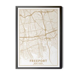 May include: A framed map of Freeport, New York, in a minimalist style. The map features a detailed street layout in gold against a white background. The town's name and coordinates are printed at the bottom. The frame is black.