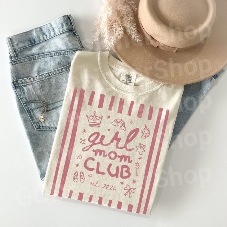 Cute pink girl mom club graphic shirt on a neutral Comfort Colors tee with girly icons, styled casually with denim, perfect for moms of girls