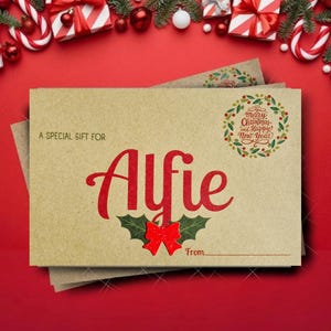 May include: A kraft paper gift card with the name "Alfie" in red script, adorned with a red bow and holly leaves. The card reads "A Special Gift For" and includes a space to write the sender's name. A festive wreath with "Merry Christmas and Happy New Year" is printed on the card.