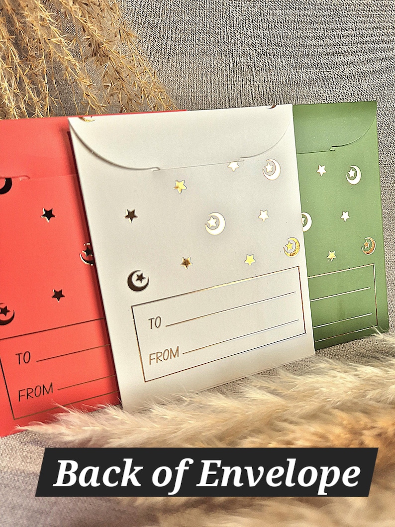 May include: Three red, white and green envelopes with gold stars and crescent moons. The envelopes have a gold line and the words "TO" and "FROM" printed on them.