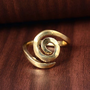 May include: A gold-toned ring featuring a spiral design. The ring is made of metal and has a simple, elegant style.