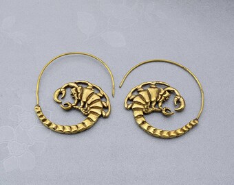 May include: A pair of gold hoop earrings featuring a scorpion design. The scorpion is detailed and intricate, and the hoops are large and dramatic.