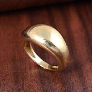 Könnte beinhalten: Ein goldfarbener Ring mit einem glatten, abgerundeten und leicht gewölbten Band.