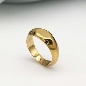 May include: A gold signet ring with a smooth, rounded top and five small star cutouts.