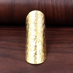 May include: A gold-colored, textured, wide ring with a floral design.