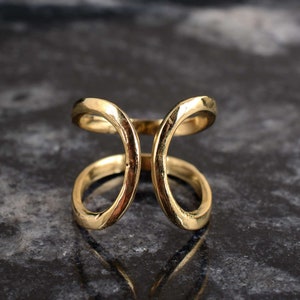 May include: Gold ring with a unique, open design featuring two intersecting circles.