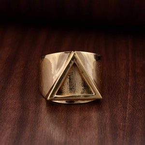 Op de afbeelding: Een gouden ring met een driehoekig ontwerp. De ring is gemaakt van metaal en heeft een gladde afwerking.
