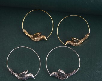 May include: Four hoop earrings with a bird design. Two earrings are gold and two are silver.