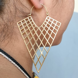 May include: Gold geometric hoop earrings with a diamond pattern. The earrings are large and triangular in shape.