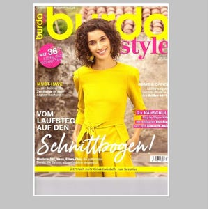Op de afbeelding: Een Burda Style tijdschriftomslag met een persoon in een mosterdgeel shirt met lange mouwen en een strikdetail in de taille. De omslag bevat opvallende gele en roze tekstoverlays, waaronder de titel Burda Style en diverse Duitse koppen.
