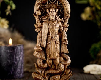 May include: A detailed wooden statue of a deity with multiple arms, a crown, and a serpent arch. The figure is carved with intricate details, standing on a lotus base. The statue is a light brown color and is set against a dark background.
