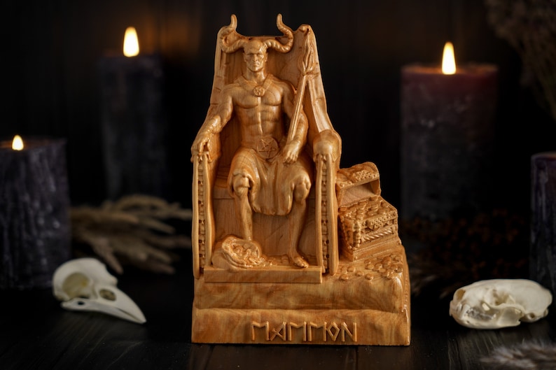 May include: Wooden statue of a demon figure sitting on a throne with a crown and a scepter. The statue is carved with intricate details and has a dark brown finish. The base of the statue is inscribed with the word "MAMMON".
