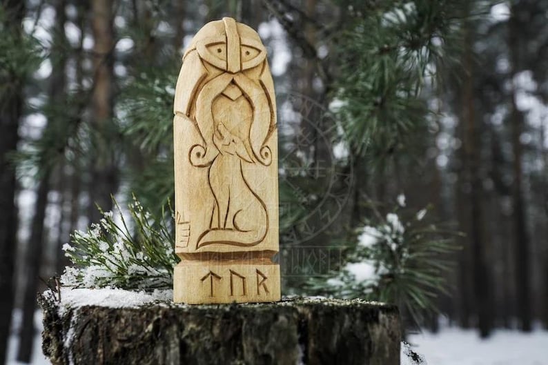 Puede incluir: Una talla de madera del dios n&oacute;rdico Thor, con un lobo a su lado. La talla est&aacute; pintada en tonos de madera natural y tiene la inscripci&oacute;n "TNR" en la parte inferior.