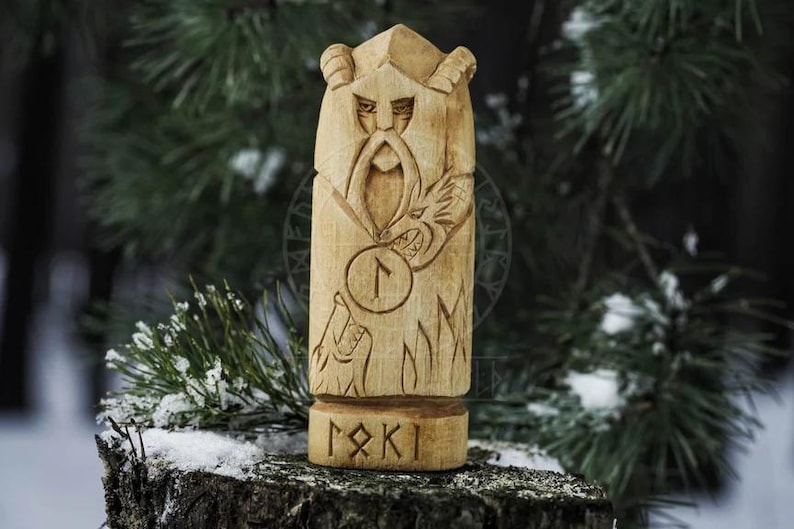 Puede incluir: Estatua de madera tallada a mano de un dios n&oacute;rdico con barba y un lobo a sus pies. La estatua est&aacute; pintada en tonos marrones y tiene un s&iacute;mbolo de runa tallado en ella. La estatua est&aacute; etiquetada como "Loki" en runas.