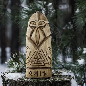 Puede incluir: Una talla de madera de un dios n&oacute;rdico con casco y barba. La talla est&aacute; decorada con un s&iacute;mbolo Valknut y la palabra "Odin" en runas.