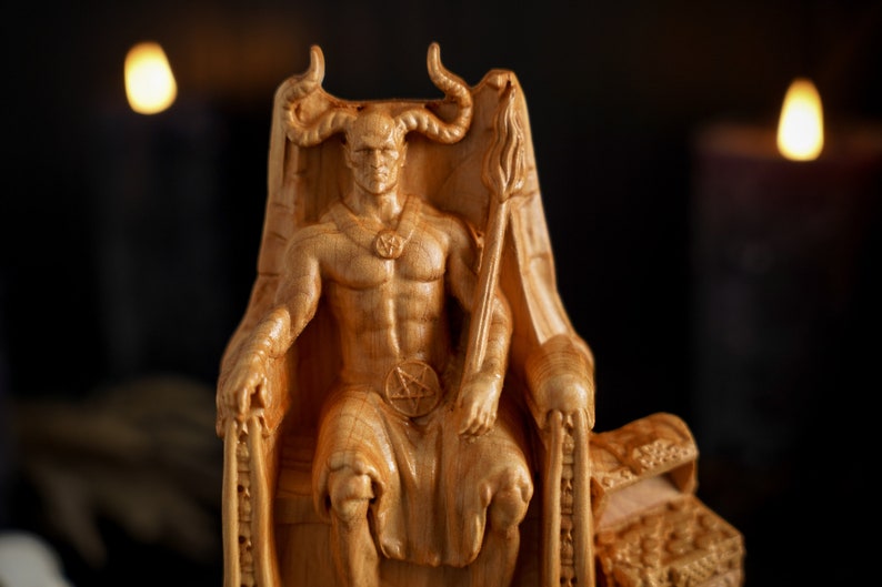 May include: A wooden sculpture of a horned figure sitting on a throne. The figure is wearing a necklace with a pentagram pendant and has a muscular build. The throne is ornately carved with details.