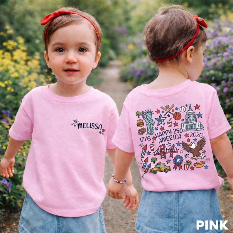 Puede incluir: Dos camisetas rosas con dise&ntilde;os patri&oacute;ticos. Una camiseta tiene el nombre "MELISSA" con estrellas. La otra camiseta presenta el texto "HAPPY 250 AMERICA 2026" con ilustraciones de la Estatua de la Libertad y un &aacute;guila.