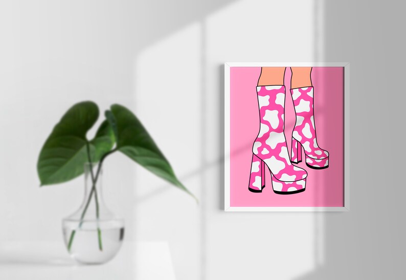 May include: A pair of pink platform boots with a white cow print design. The boots are on a pink background.