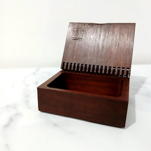 May include: A dark brown wooden box with a hinged lid, partially open. The box features a rectangular shape and a smooth finish. The lid has the text "Townsend Chemicals". The box is likely used for storage or display.
