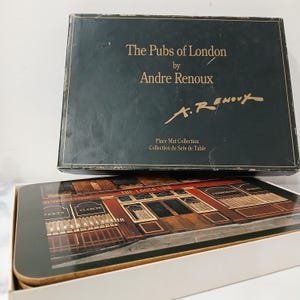 May include: A set of place mats depicting a London pub, with the text "The Pubs of London by Andre Renoux." The mats are in a box labelled "Place Mat Collection." The image shows a detailed illustration of a pub with the name "The Loose Vine".