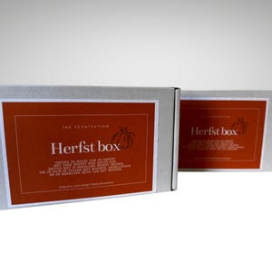 K&ouml;nnte beinhalten: Zwei rechteckige Boxen mit orangefarbenen Etiketten und wei&szlig;en R&auml;ndern. Auf den Etiketten steht "Herfst box" mit Text darunter auf Niederl&auml;ndisch. Die Boxen sind f&uuml;r "The Scentsation".