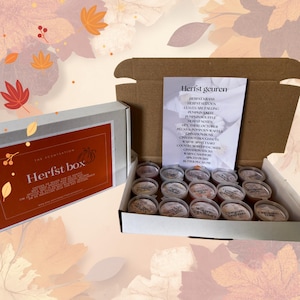 K&ouml;nnte beinhalten: Eine offene Schachtel mit runden Wachsschmelzen mit Etiketten. Eine wei&szlig;e Schachtel mit dem Text "Herfst box" befindet sich links. Ein Papier listet die D&uuml;fte auf, darunter "Pumpkin Souffle" und "Cinnamon Buns."