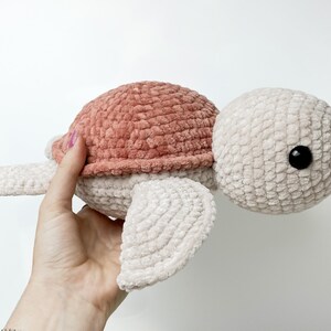 Pu&ograve; includere: Un giocattolo di peluche di tartaruga all'uncinetto con un guscio rosa e un corpo bianco. La tartaruga ha un occhio nero ed &egrave; realizzata con un filato morbido e peloso.