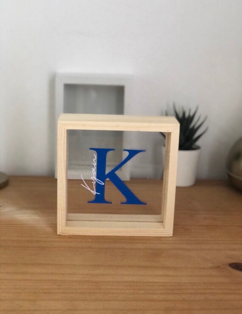 May include: A wooden frame with a clear acrylic insert featuring a blue letter K and the word "your" in white script.