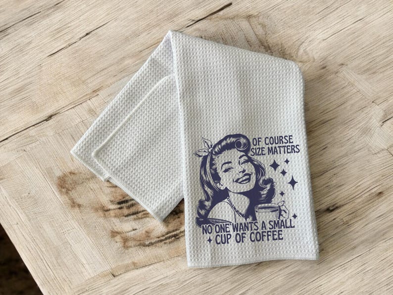 May include: A white kitchen towel with a blue retro-style illustration of a woman with a large cup of coffee. The text reads "Of course size matters. No one wants a small cup of coffee."