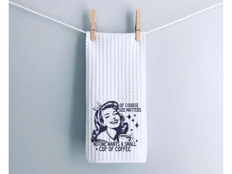 May include: White waffle weave kitchen towel with a black and white illustration of a woman holding a coffee cup. The text reads "Of course size matters. No one wants a small cup of coffee."