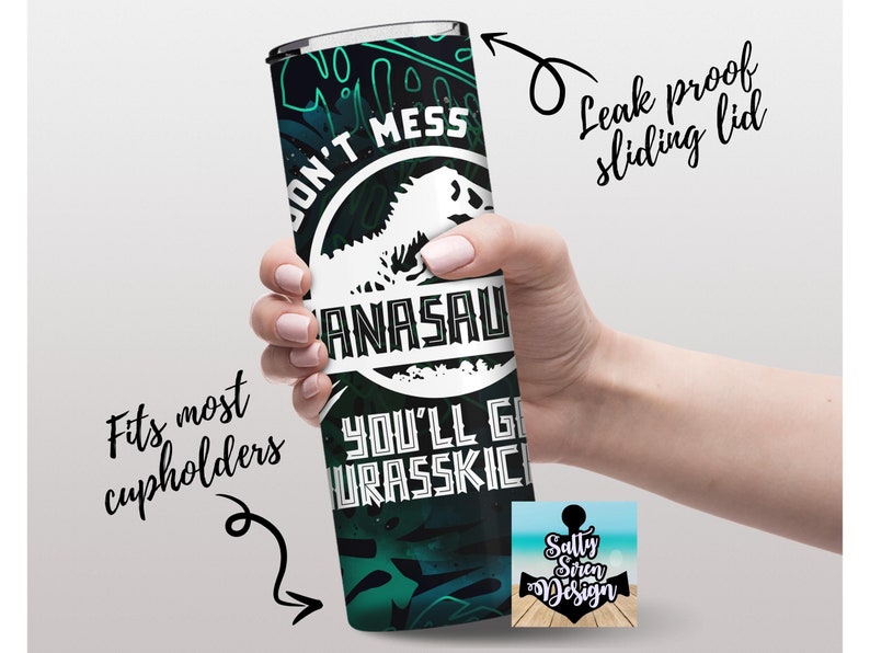 Puede incluir: Un vaso de acero inoxidable verde y negro con un gr&aacute;fico de dinosaurio y el texto "Don't Mess with a  Anasaurus You'll Get Urasskiched". El vaso tiene una tapa deslizante a prueba de fugas y se adapta a la mayor&iacute;a de los portavasos.