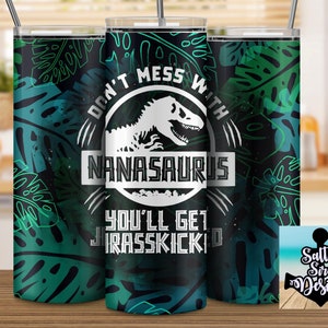 Puede incluir: Un vaso negro y verde con un gr&aacute;fico blanco de un dinosaurio y el texto "Don't mess with Nana-saurus you'll get Jurassic-kicked".