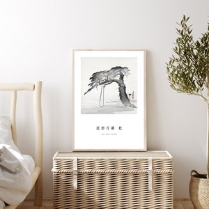 May include: A black and white ink painting of a tree with a swing hanging from its branches. The painting is framed and hanging on a white wall above a wicker chest. The text "北 庐 月 昨" is written in black ink below the painting.