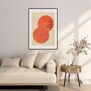 May include: A framed print of a minimalist abstract art piece featuring two overlapping orange circles with a pattern of small grey flowers on a cream background.