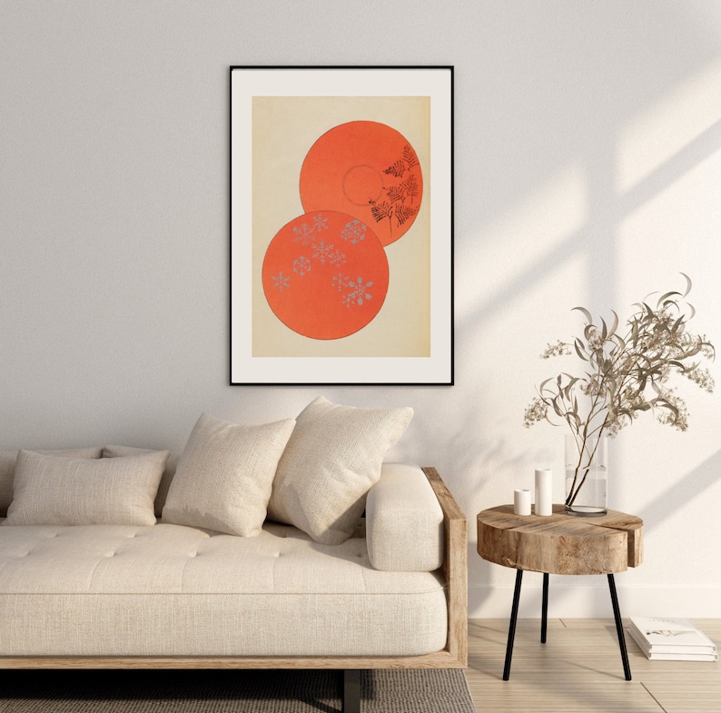 May include: A framed print of a minimalist abstract art piece featuring two overlapping orange circles with a pattern of small grey flowers on a cream background.